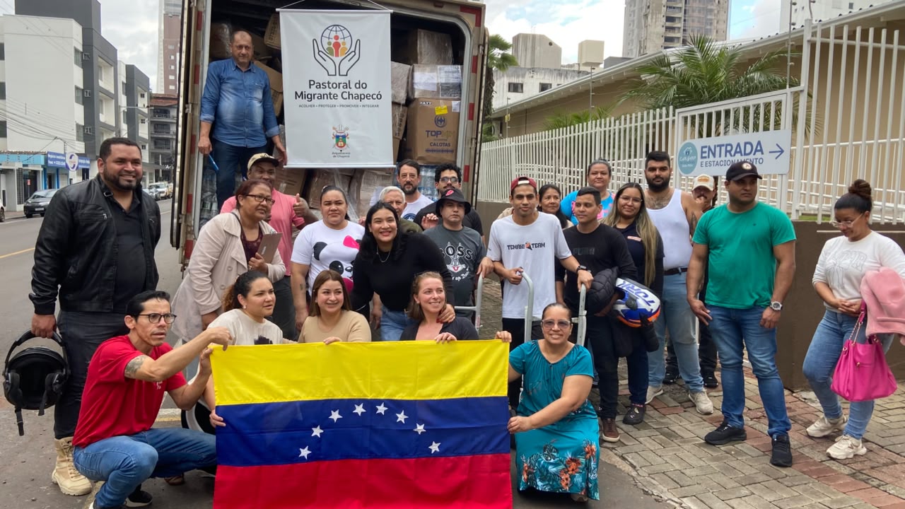 Voluntários da Pastoral do Migrante Chapecó carregam caminhão com doações, com a bandeira da Venezuela